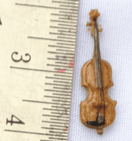 A tiny violin, about 2 centimeters long is on the right; to the left is a ruler in centimeters.