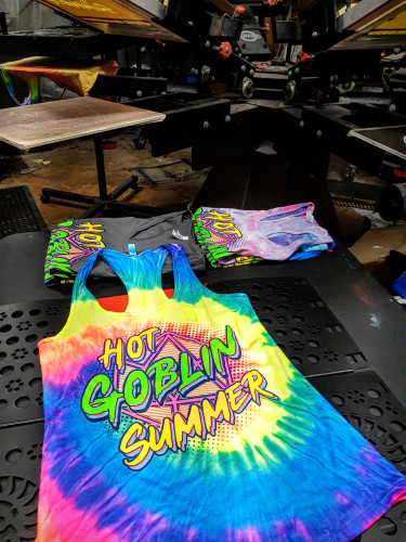 A few hot goblin summer tank tops in the foreground, the printing press in the background 