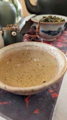 Oolong tea in a bowl as a tea pet looks on.