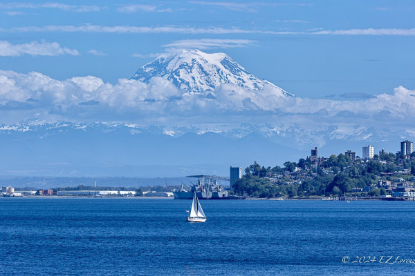 View of Tahoma over the waters of Puget Sound with a white sailboat. 
