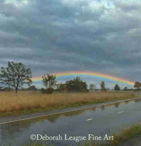 Rainbow over a country road. On a rainy day my daughter and I were traveling on a secondary road to avoid traffic congestion. The rain had become very light and a beautiful rainbow appeared in the sky. We pulled over and took this magical photo.