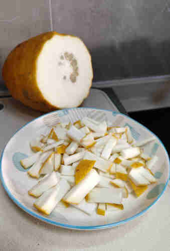 big citrus with a chunk cut off, pieces of citrus peel on a plate 