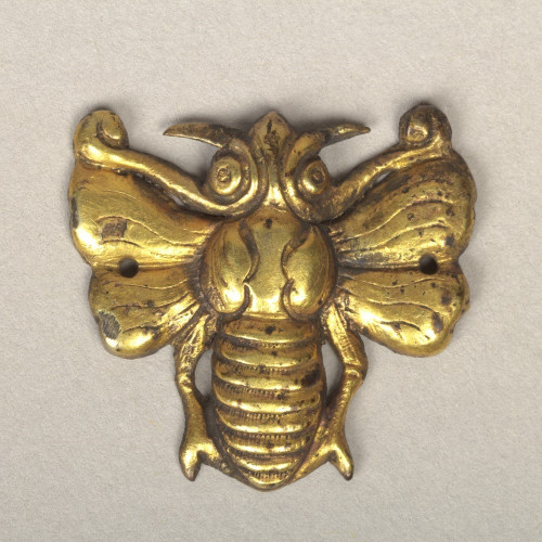 official museum photo of the object, top-down profile on grey background: small gold costume ornament in the shape of a striped bee with open wings, brighter golden yellow color than next example