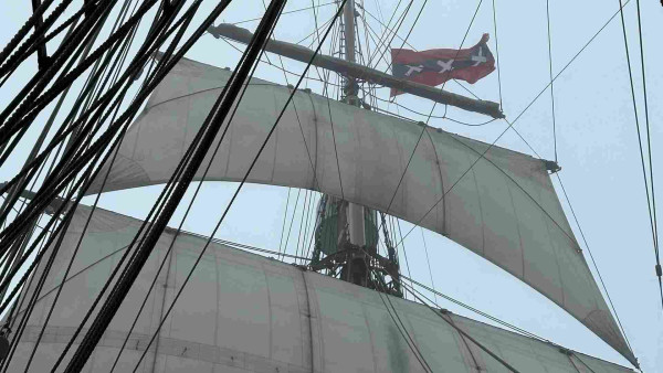 Amsterdam flag seen through heavy fog at the top of the mizzen mast with two square sails set