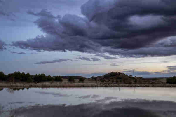 Foto de un paisaje al final del atardecer (en la hora azul) en el cual se ve una gran nube.

Photo of a landscape at the end of sunset (at blue hour) with a big cloud.