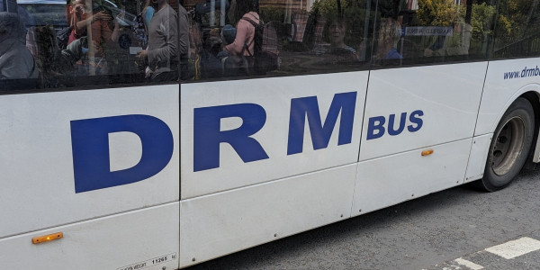 A white bus with blue text on the side reading "DRM BUS"