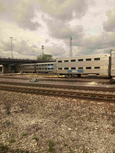 Large metallic trains that look quite 60s with two clear levels inside. Blue Metra logo on the side.