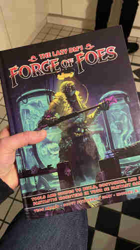 A person holding a hardback book of THE LAZY DM’S FORGE Of FOES
TOOLS AND GUIDES TO BUILD, CUSTOMIZE, AND RUN
FANTASTIC MONSTERS IN YOUR 5E FANTASY GAME. 