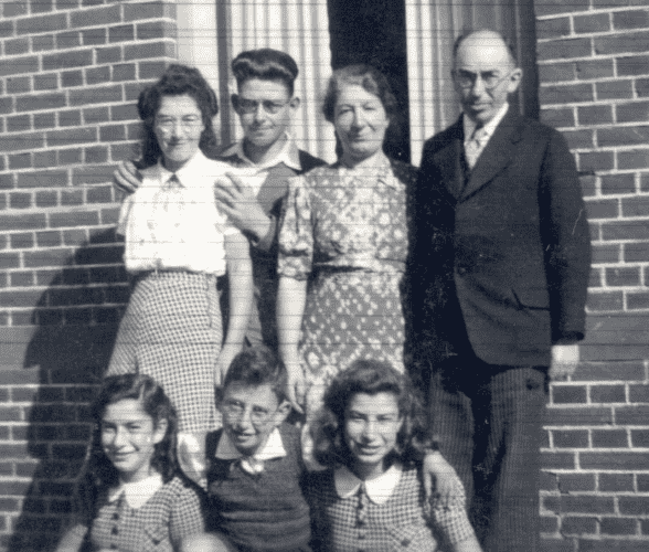 photograph of Heiman Akker, Judikje Akker-Heiman and their five children, Leentje en Izak standing next to their parents, Carolina, Aron Jacob and Henriëtte, sitting in front on them. The photo location is in front of their house, address Broerstraat 8, Appingedam. 
