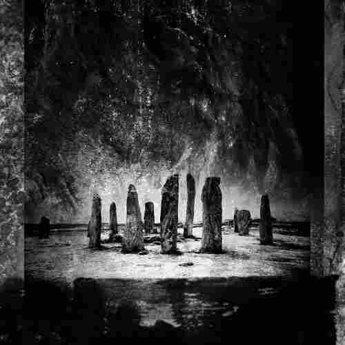 Black and white image of tall standing stones, with textured overlays creating a dramatic atmosphere.