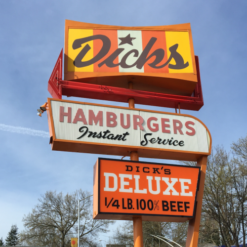 Old drive-in signs reading "Dicks", " Hamburgers Instant Service", "Dick's Deluxe 1/4 lb. 100% Beef"