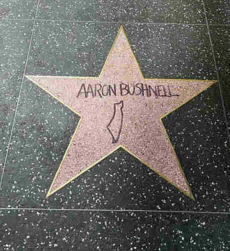 A photo of an actual blank Hollywood Blvd star marked up in black ink to read "Aaron Bushnell" and a map of Palestine.