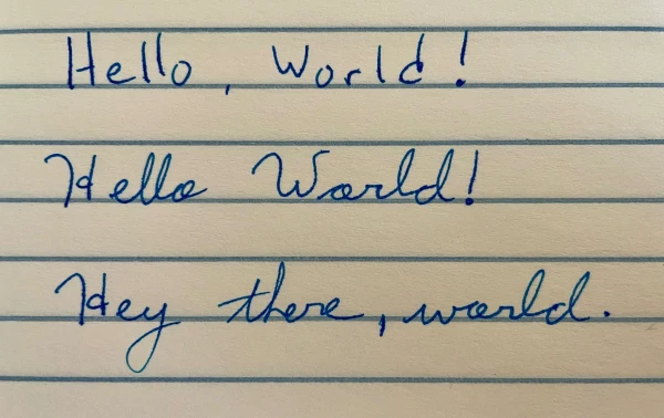 Handwritten note in blue ink on yellow paper with blue ruled lines. 

"Hello, World!"  -- printed
"Hello World!" -- cursive
"Hey there, world." -- also cursive