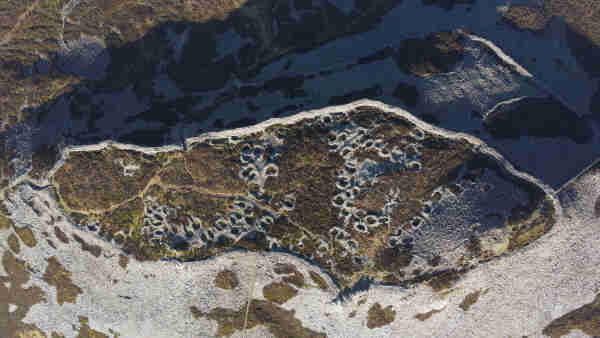 Vertical drone view of a large hillfort complex, showing several tens of roundhouse stone wall bases.