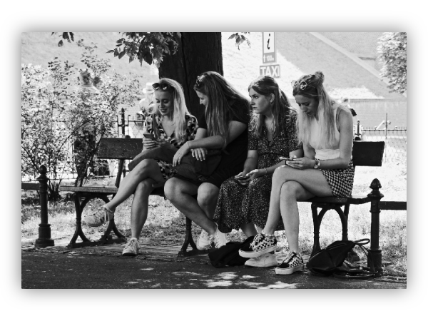 Four girls on park benches.