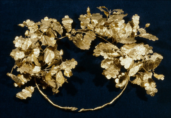 Description from the museum: “This wreath consists of two branches. At the back the stems have obliquely cut end-plates; at the front the two branches are held together with a split pin fastener that has a bee as its cap. The branches are made of sheet-gold tubes, over a modern copper core. Each branch has six sprays with eight leaves and seven or eight acorns, as well as a cicada. In addition, there are about a dozen single leaves set straight into each branch. The leaves are of three different sizes and are made in one piece with their stalks. The acorns are made in left and right die-formed halves; the cups are cross-hatched and there is a point on the top of the fruit. The cicadas are constructed from four separate sheets of gold - lower body, upper body, two wings.”