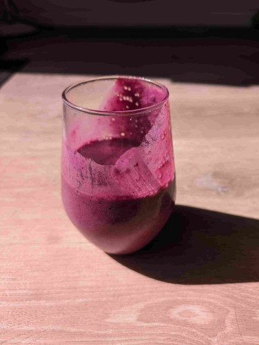 A wine glass full of creamy purple goo. Half of it has already been consumed and it coats the inside of the glass where it was tipped to drink.