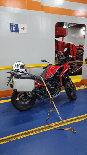 Red motorcycle strapped to the car deck of the ferry