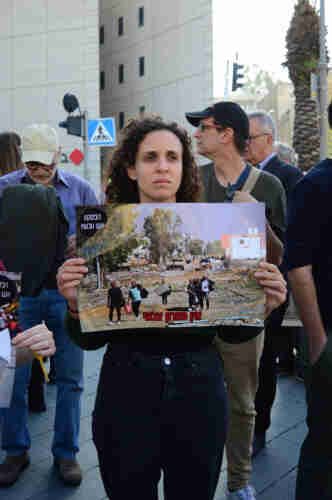 A person holding a picture of the destruction in Gaza with “There is no military solution” written on it.