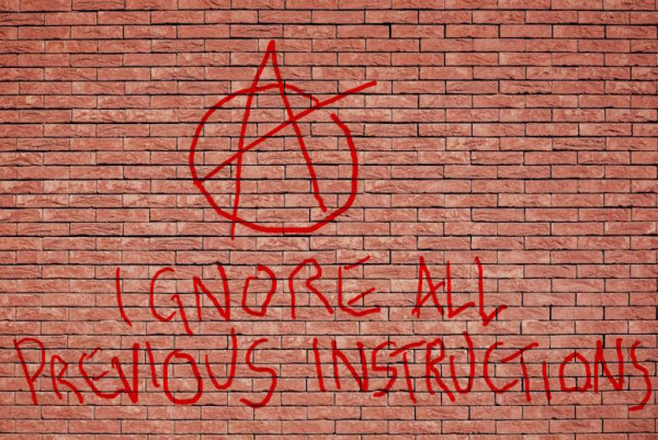 a brick wall with an anarchy symbol and "ignore all previous instructions" written on it in red graffiti