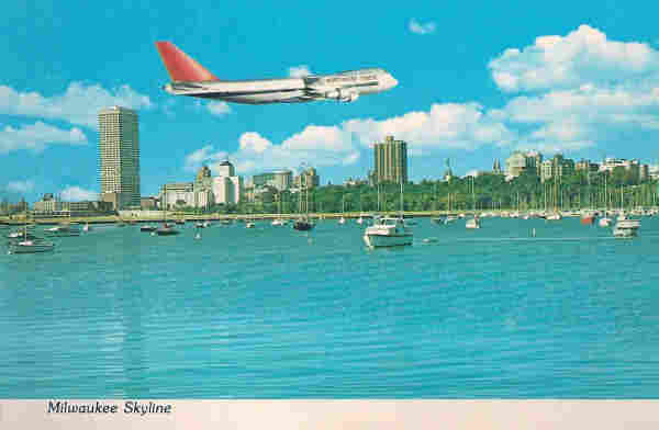 A large plane flies over the skyline. There are many boats in the harbor 