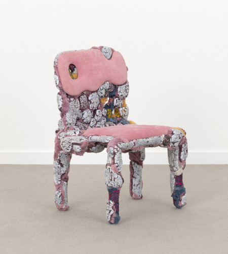 Sculptural chair covered in droopy pink upholstery and mottled pink/magenta tiles
