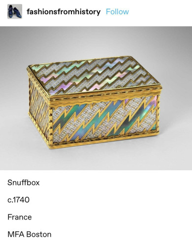 Photo of a French snuffbox from 1740. It is a small rectangular box with gold lightening flashes and opalescent designs