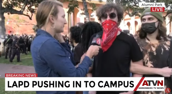 Student protester in red mask speaks with reporter on the University of Southern California campus. 