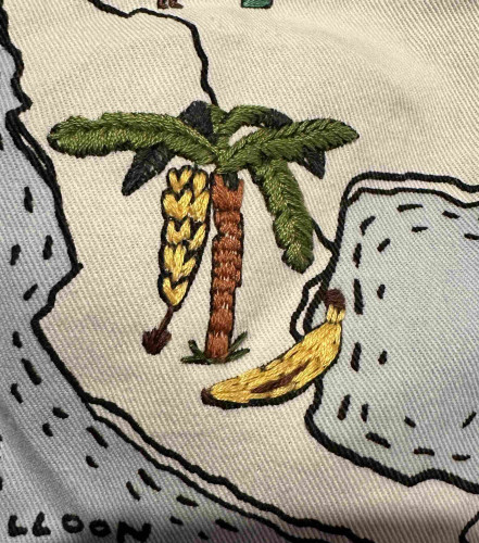 A small embroidered banana tree and an embroidered banana. They’re next to each other and the scale make them look odd. 