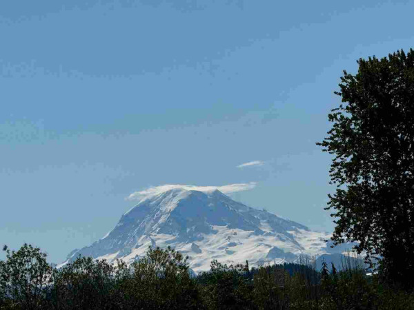 A snowy stratovolcano at the horizon, viewed from Sumner, Washington. 