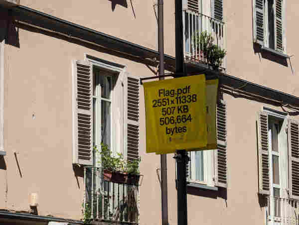 A yellow banner on a lamppost. In block sans serif caps, it reads: 

FLAG.PDF
2551X11338
507 KB
506,664 bytes