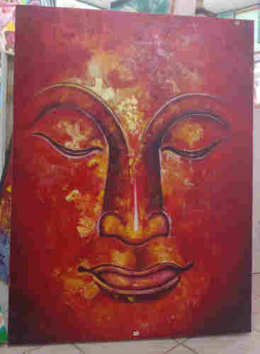 a painting of the face of the buddha, his eyes low in meditation, painted with strong reds with yellow in the middle part