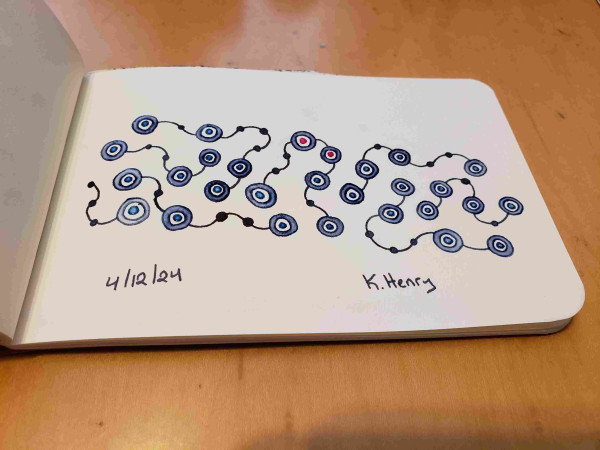 Hand drawn generative art in ink on an open page of my sketchbook. The abstract pattern looks a bit like some strings with beads on them. Two of the beads have hot pink centers.