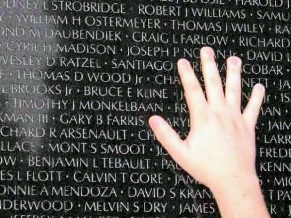 Hand reaching up to the name Craig L. Farlow on the Vietnam Memorial wall.