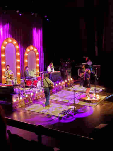 Six member band Waxahatchee with lead singer Katie Crutchfield on a small podium at the front of the stage perform at Toronto's Massey Hall