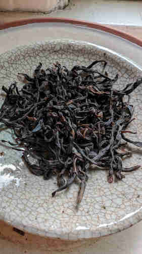 Dry Dancong Oolong leaves on a crackled plate.