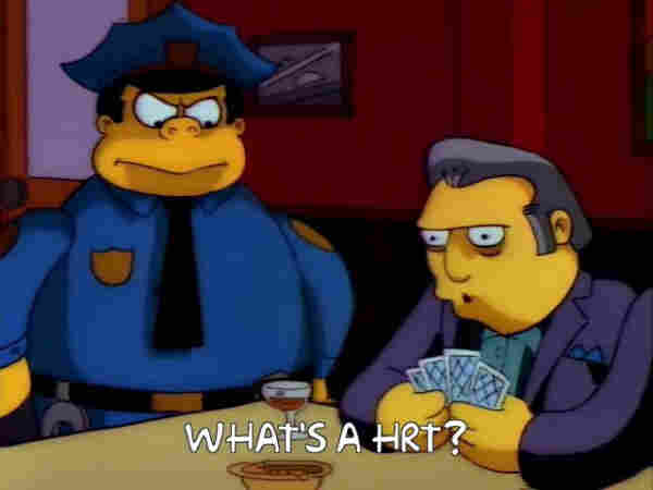 Screen cap from The Simpsons. An annoyed looking Chief Wiggum is looking at Fat Tony playing cards. The caption says "What's a HRT?"
