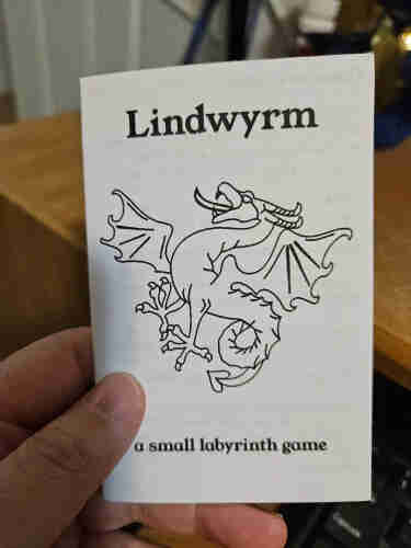 The front cover of a 1/8th page mini zine, black and white, titled Lindwyrm.  The cover has the title, lineart of a rampant lindwyrm/wyvern, and the subtitle "a small adventure game".
