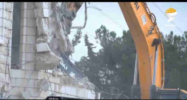 screen capture of Israeli backhoe destroying an apartment complex in Jerusalem.