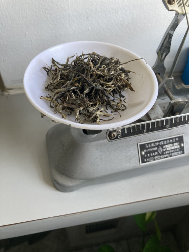 Twisted large green tea leaves in a mechanical balance scale 