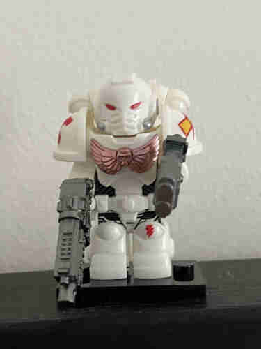 A toy Lego style - A Warhammer SpaceMarine figure - a futuristic white armored soldier with red eyes and accents, holding a gun, standing against a plain background.