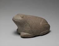 a smooth, rounded, fairly abstract stone sculpture of a frog. it's sitting very calmly.
