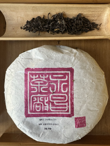 Tea cake in wrapper and dry tea leaves 