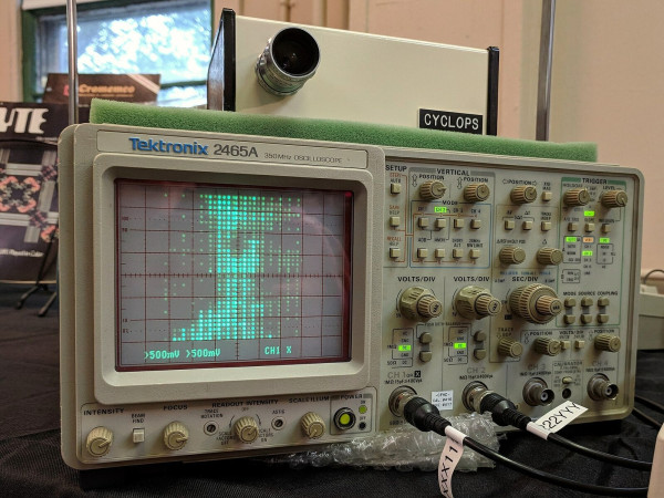 person rendered with 32x32 pixels on an analog oscilloscope screen, with a boxy camera labeled "CYCLOPS" sitting above it