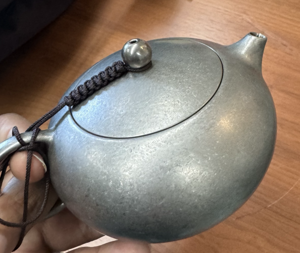 A Chinese style xi shi teapot, round with a little cord to hold on the lid but instead of yixing it is titanium. 