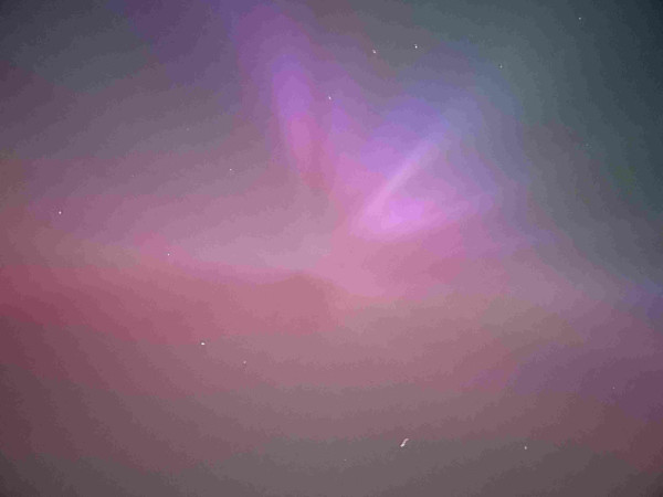 A pink-red aurora with flares in all directions