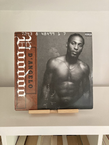 Vinyl record cover of D'Angelo’s Voodoo, featuring the artist, shirtless with braided hair.
