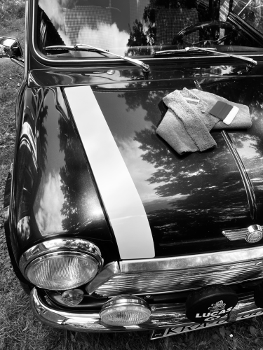 Black and white photography showing a section of a Rover Mini Cooper car produced in 1994, which I have owned for several years. The car has undergone an absolutely complete restoration and the photo shows the branding moment. I have just applied stickers in the form of stripes on the bonnet of the car at the front and on both sides of the body lengthwise. These stickers are typical to this car only.