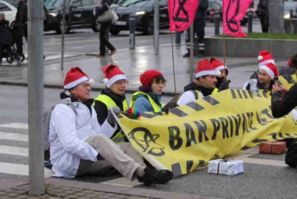 Scientists and activists blocking Kastrup airport, while holding a sign that reads "Ban Private Jets"
