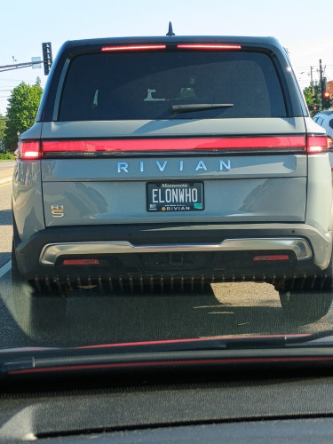 A Rivian electric car with a Minnesota blackout plate that reads "Elon Who"